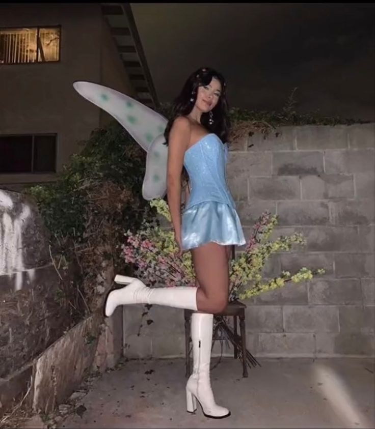 a woman in a blue dress and white boots is posing with a fairy costume on