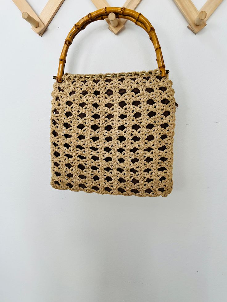 "Boho vibes abound with this free spirited crochet bag. Or maybe it's granny chic. Whatever it is, I think it's adorable and charming Crochet is back on trend and this bag is a beautiful example. Beautiful lace pattern in a natural neutral color palette Charming neutral brown fabric lining Gorgeous curved bamboo handles Perfect for the beach or the farmers market. Or use it as your everyday purse. Measures: 12.5\" x 12\"" Handheld Crochet Bags For The Beach, Handheld Crochet Shoulder Bag For Beach, Bohemian Rectangular Straw Bag For Daily Use, Bohemian Style Rectangular Straw Bag For Daily Use, Bohemian Style Spring Tote Straw Bag, Handheld Brown Crochet Bag For Spring, Crochet Handheld Shoulder Bag For Beach, Vintage Shoulder Bag For Everyday Summer Use, Bohemian Shoulder Bag With Top Handle In Natural Color