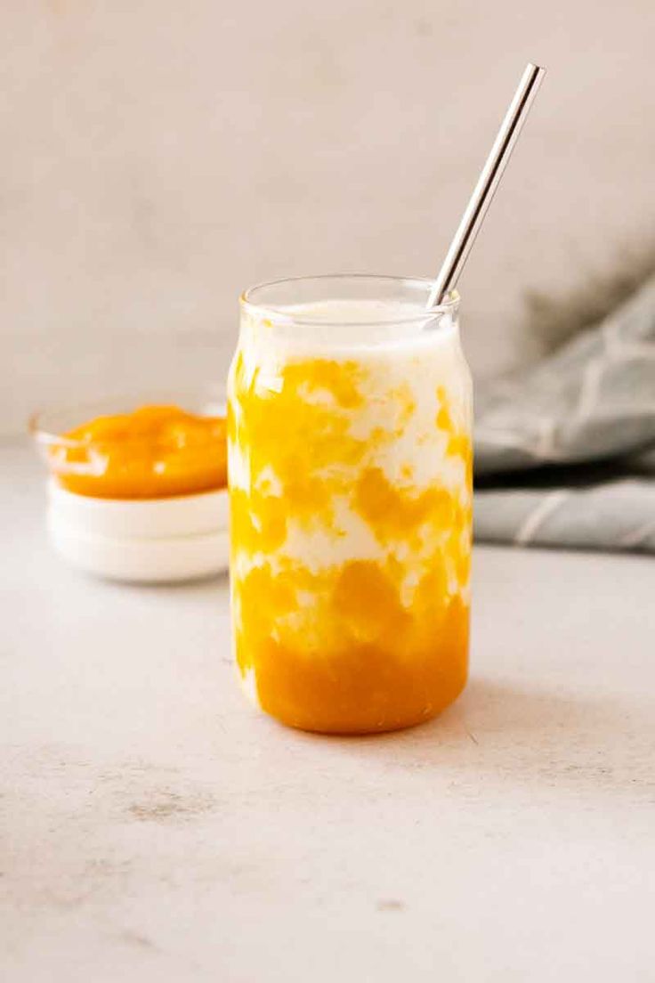 a glass jar filled with liquid sitting on top of a counter next to a spoon