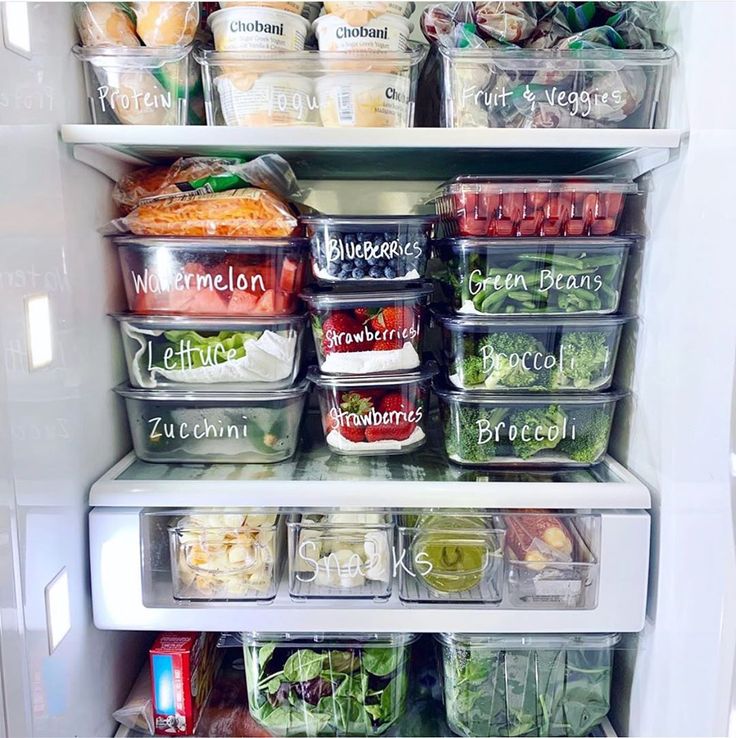 an open refrigerator filled with lots of food and containers on the shelves in front of it