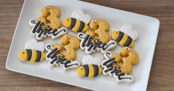 decorated cookies on a white plate with black and yellow lettering that says, we hope the bees