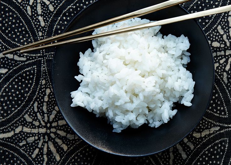 white rice and chopsticks in a black bowl