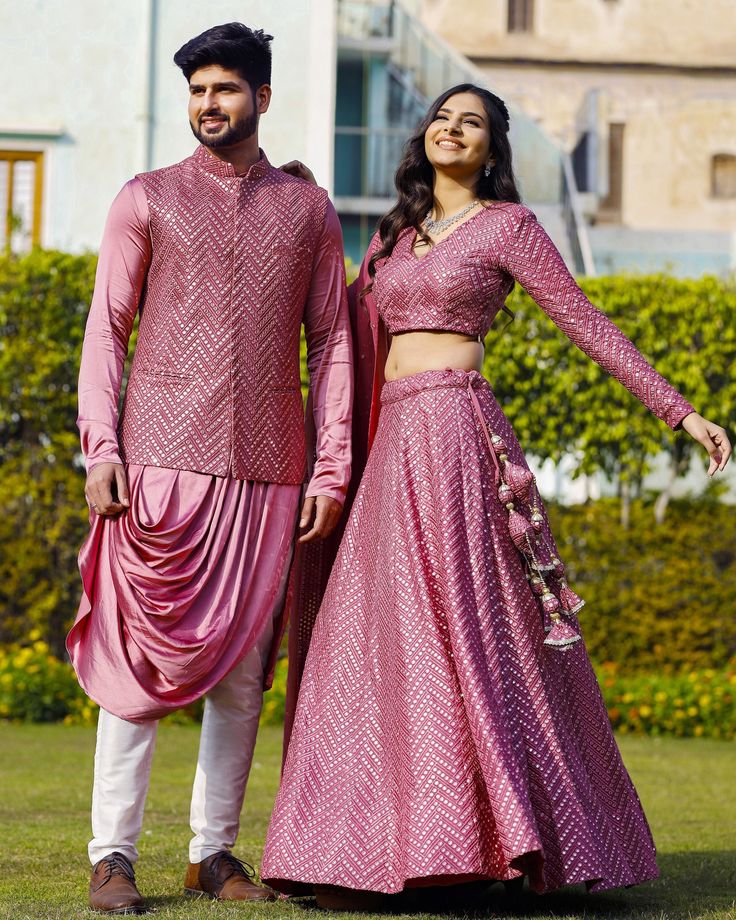 Menswear:- Satin Cowl Style Kurta in Pink.This Readymade attire with Satin Lining is Enhanced with Pockets, Mirror Effect and Resham Work. Crafted in Chinese Collar Neck and Full Sleeve Available with a Cotton Aligarhi Pant in White and a Faux Georgette Nehru Jacket in Pink Lehenga Choli:- Readymade Faux Georgette Lehenga in Pink This attire with Shantoon and Cotton Lining is Enhanced with Fancy Tassels, Side Zip, Resham and Mirror Work. Available with a Faux Georgette Pink Choli Crafted in V Ne Mirror Work Couple Outfit, Kurta And Lehenga, Pink Choli, Fancy Tassels, Indian Jackets, Georgette Kurta, Georgette Lehenga, Mens Sherwani, Resham Work