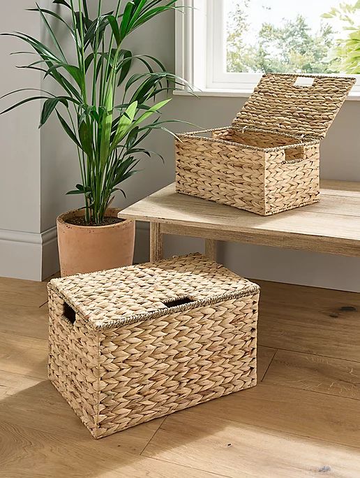 three wicker baskets sitting on top of a wooden table next to a potted plant