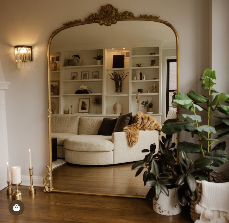 a living room filled with furniture and a large mirror on top of a hard wood floor