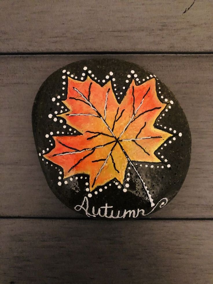 a painted rock with an autumn leaf on it