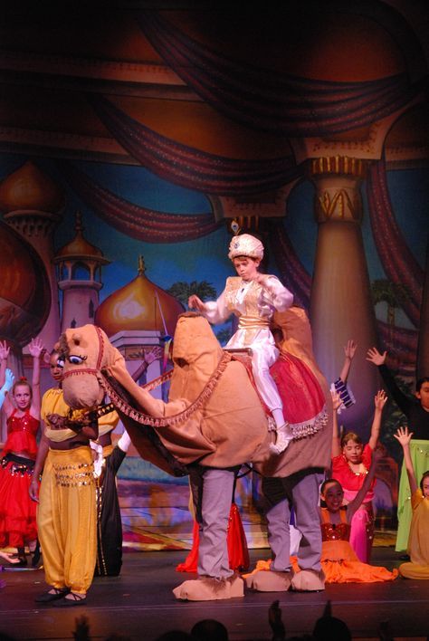 children on stage with an elephant and man in costume