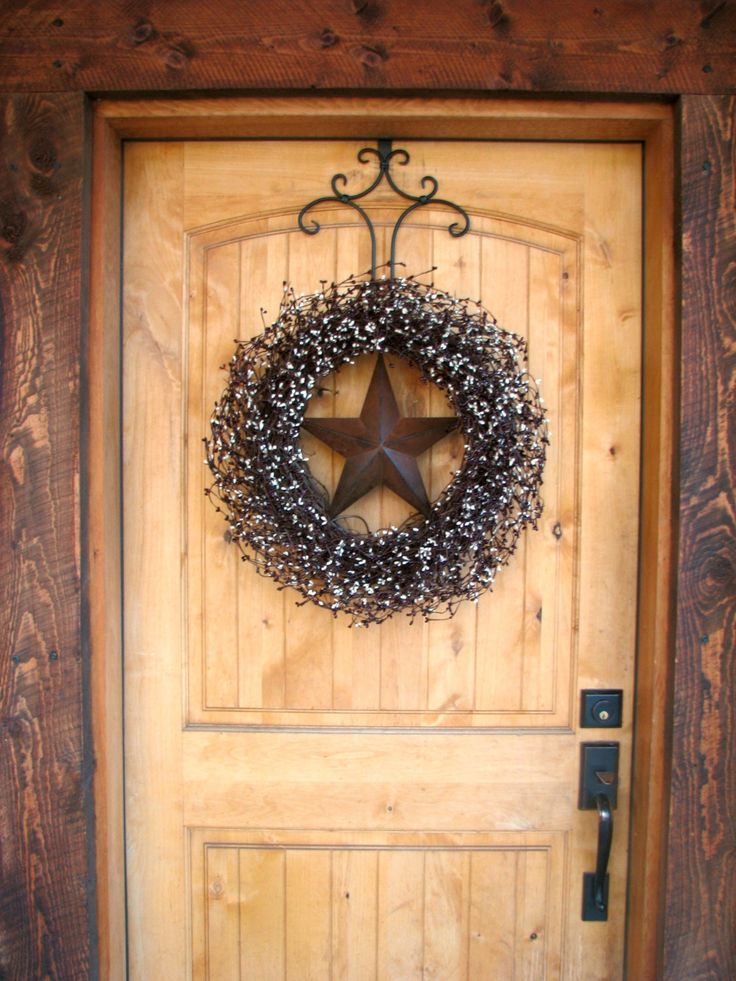 a door with a wreath on it and a star hanging from the front door frame