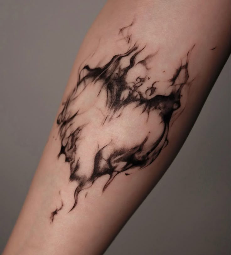 a black and white photo of a tattoo on someone's arm with ink swirling around it