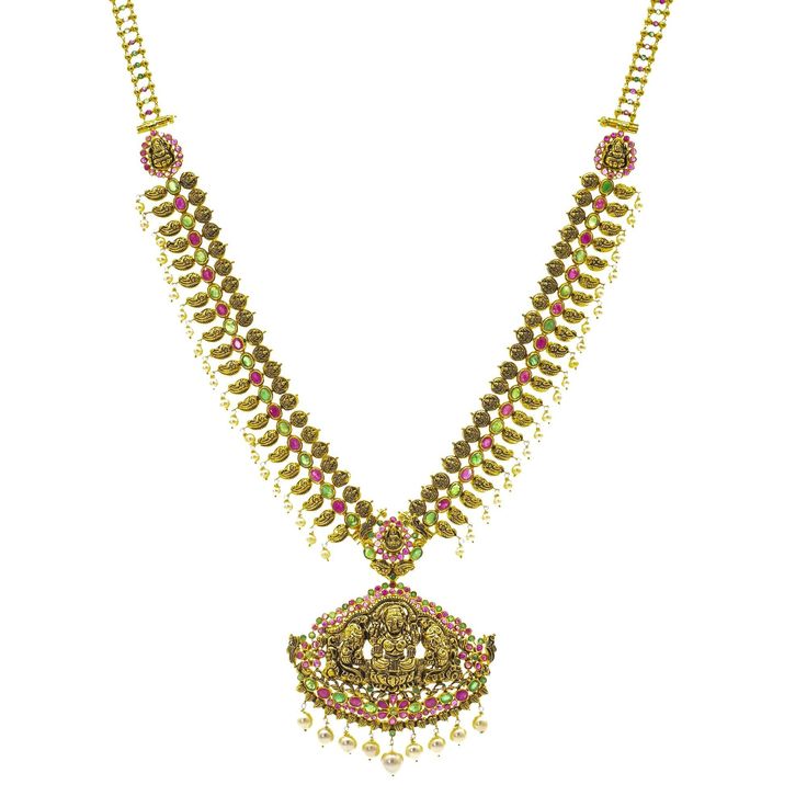 Show off your one-of-a-kind style with this stunning 22K gold necklace set from Virani Jewelers! Features an antique Laxmi pendant Made with Virani’s signature 22K gold Embellished with emeralds, rubies, and pearls Designed with a hook-in-eye clasp There’s no better way to share your culture with others than with jewelry, and at Virani Jewelers, we offer a variety of pieces featuring deities and more! This gorgeous 22K gold necklace set features a pendant depicting Laxmi and has a unique antique Temple Style 22k Gold Kundan Necklace With Gemstones, Festival Green Kundan Necklace In 22k Gold, Temple Jewelry Necklace In Yellow Gold With Gemstone, Yellow Gold Chandbali Temple Necklace, 22k Gold Green Temple Necklace For Celebration, Yellow Gold Temple Necklace With Gemstone For Festivals, Traditional Green Emerald Necklace In 22k Gold, Yellow Gold Gemstone Temple Necklace For Festivals, Gold Emerald Necklace With Intricate Temple Jewelry Design