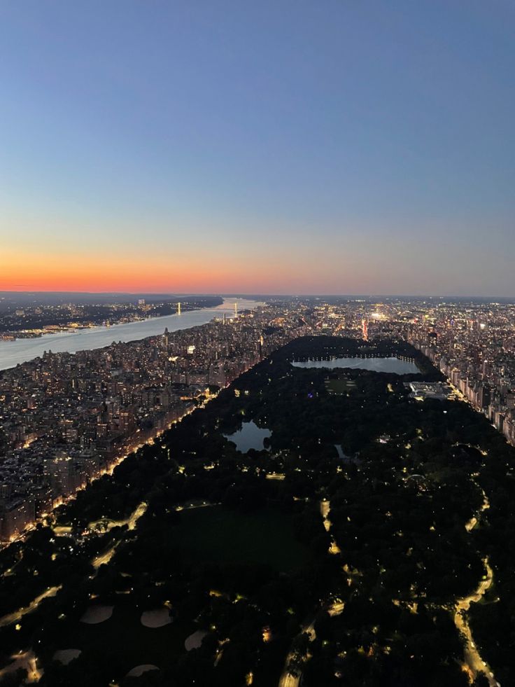 an aerial view of the city lights and water at night from above, looking down on central park