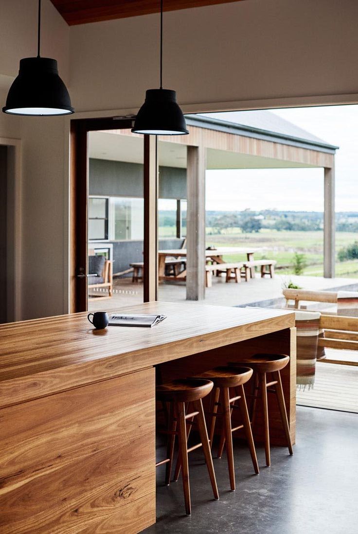 a kitchen with wooden counter tops and stools in front of an open door that leads to a covered patio