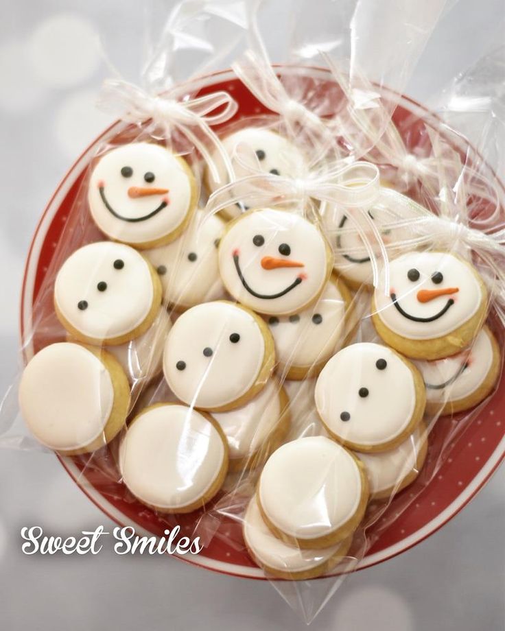 frosted snowman cookies on a red plate with clear plastic wrapper around them