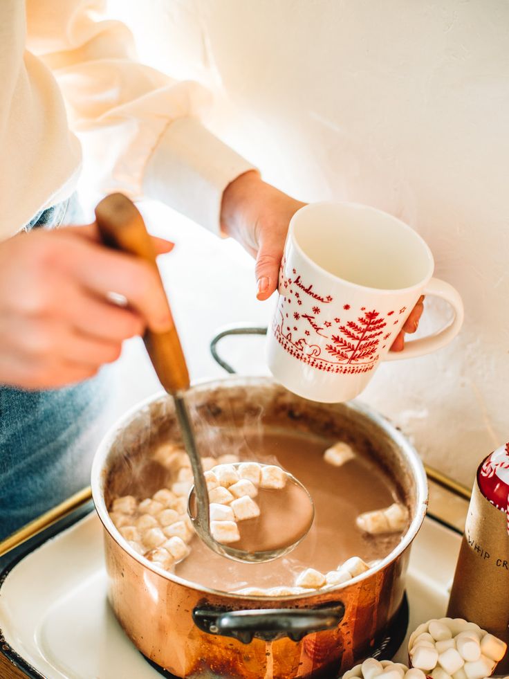 a person stirring marshmallows in a pot with a spoon