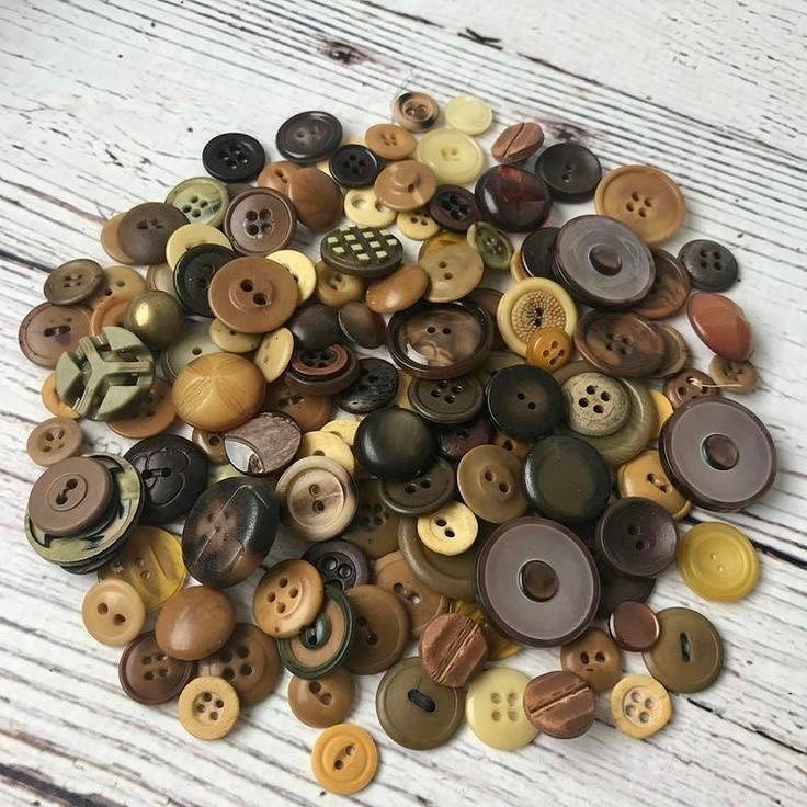 a pile of buttons sitting on top of a white wooden table next to each other