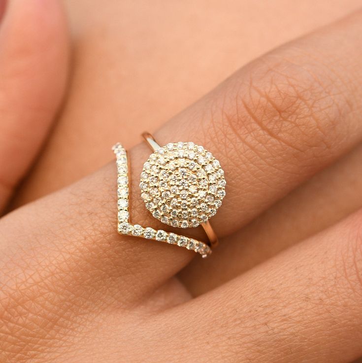 a woman's hand with a diamond ring on top of her finger and an open gold band around it