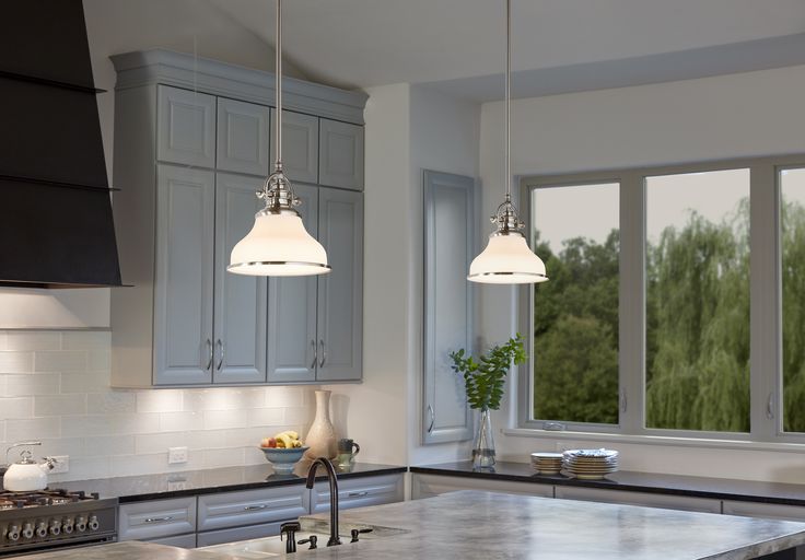 a kitchen with two lights hanging from the ceiling and an island in front of it