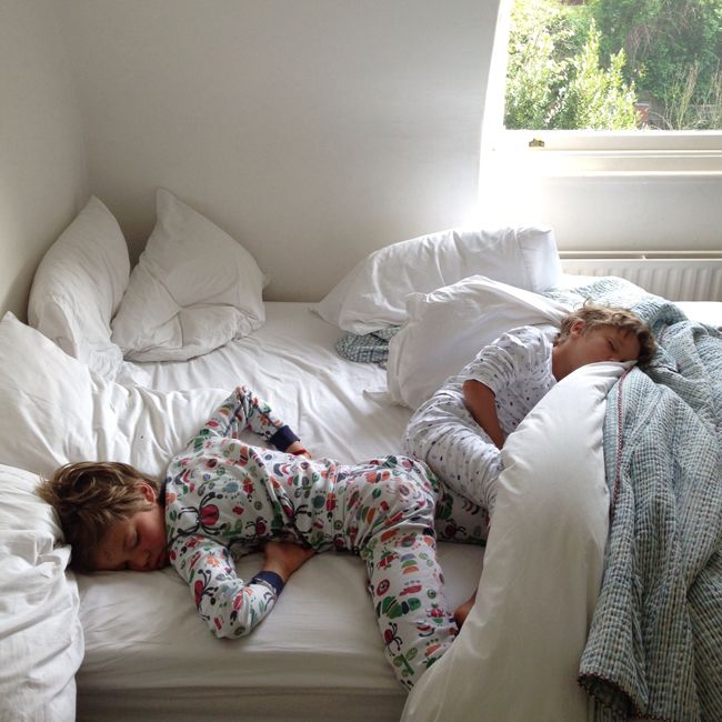 two children are sleeping on the bed in their pyjamass and blankets