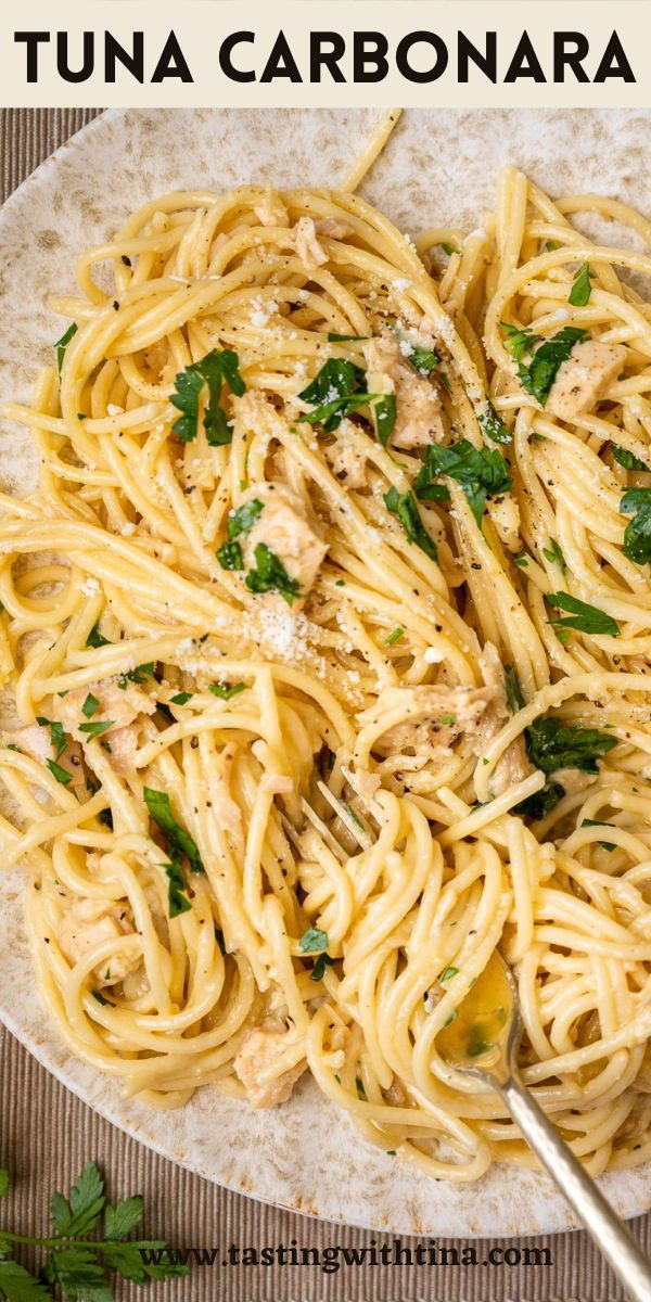 a white plate topped with pasta covered in sauce and garnished with parsley