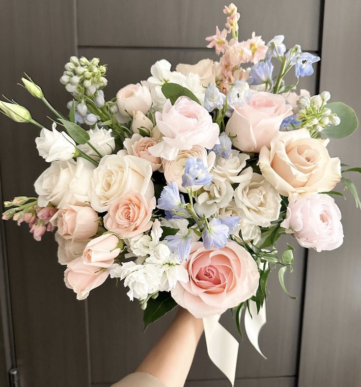 a person holding a bouquet of flowers in their hand with the background painted gray and white