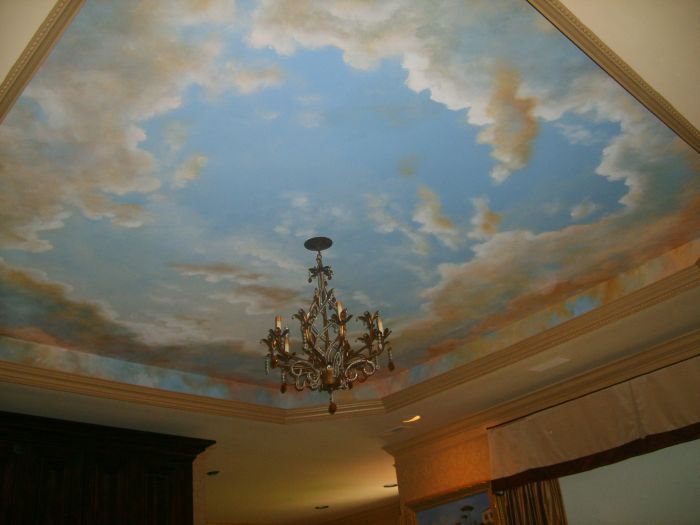 a chandelier hanging from the ceiling in a room with clouds painted on it