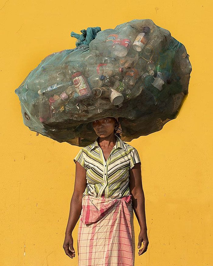 a woman carrying a large bag on her head with bottles all over the top of her head