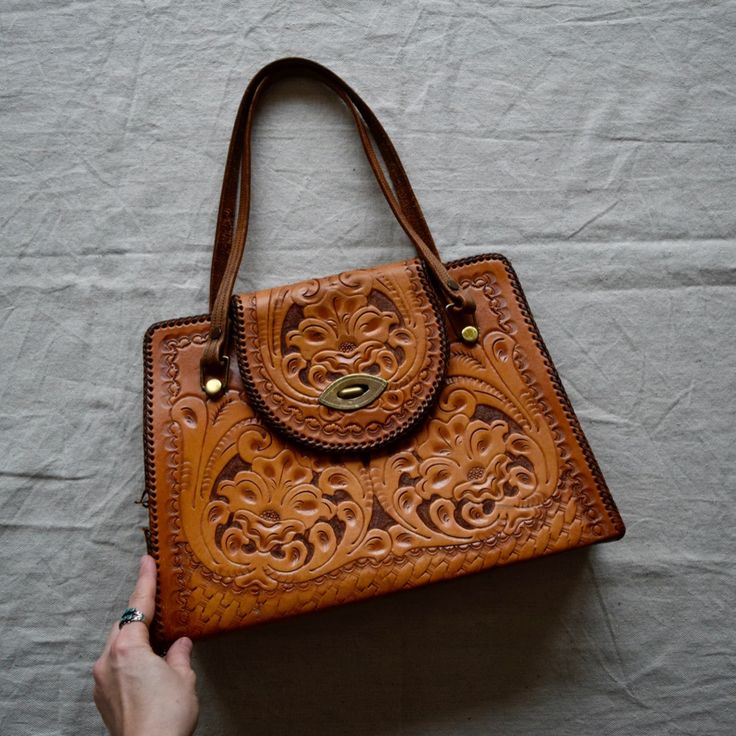 Stunning Large Size Hand Tooled Leather Purse By Clifton's. Features Brass Hardware, Western Braided Edges And Several Interior Pockets. Some Wear To The Leather And Brass And A Few Small Sections Of Broken Stitching Along Edge, See Photos. Strap Is Long Enough To Use As A Shoulder Bag. 14.5" Wide X 10.5" Tall X 3" Depth Straps 22" End To End Thank You For Looking And Don't Hesitate To Reach Out With Any Questions. Follow Along On Social @Elcaminovintage Vintage Satchel Shoulder Bag For Errands, Vintage Satchel With Removable Pouch For Errands, Retro Leather Bag With Detachable Handle, Vintage Shoulder Bag With Leather Handles For Errands, Vintage Satchel Bag For Errands, Vintage Leather Bag With Top Carry Handle, Retro Rectangular Bag With Leather Lining, Retro Top Handle Bag With Leather Lining, Retro Cognac Shoulder Bag For Daily Use