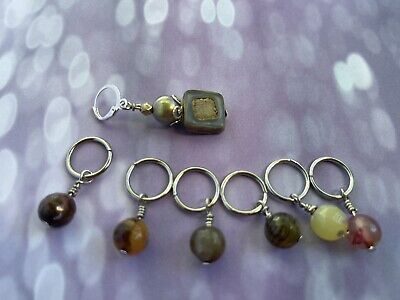 six different colored beads and silver rings on a purple background with white lights in the background