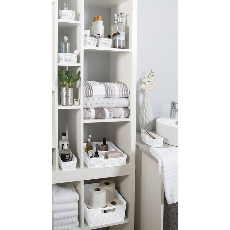 a bathroom with white shelves filled with towels and toiletries