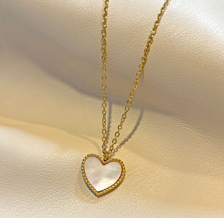 AMIRI HEART PEARL PENDANT NECKLACE Fall in love with the AMIRI HEART PEARL PENDANT NECKLACE, available in gold and rose gold! Its high polish finish and iridescent mother of pearl shell heart pendant will add a touch of elegance and romance to any outfit. The perfect gift for someone special or a treat for yourself. Materials: Stainless steel, 18k gold plated Measurement: necklace length 16” extension length 2" Total length 18” Pendant width: 16mm W x 12mm H Closure: lobster clasp Additional Inf Everyday Jewelry Gold, Shell Heart, Dope Jewelry, Jewelry Outfit, Pearl Pendant Necklace, Sustainable Jewelry, Pearl Shell, Recycled Gold, Rose Gold Necklace