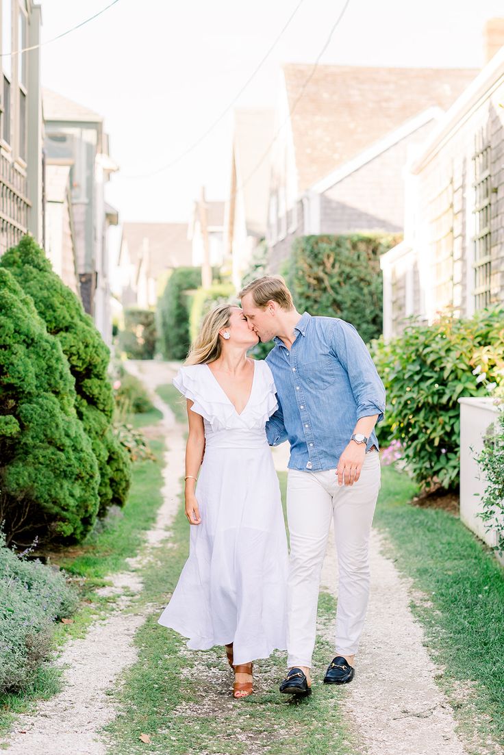 an engaged couple walking down a path in front of houses