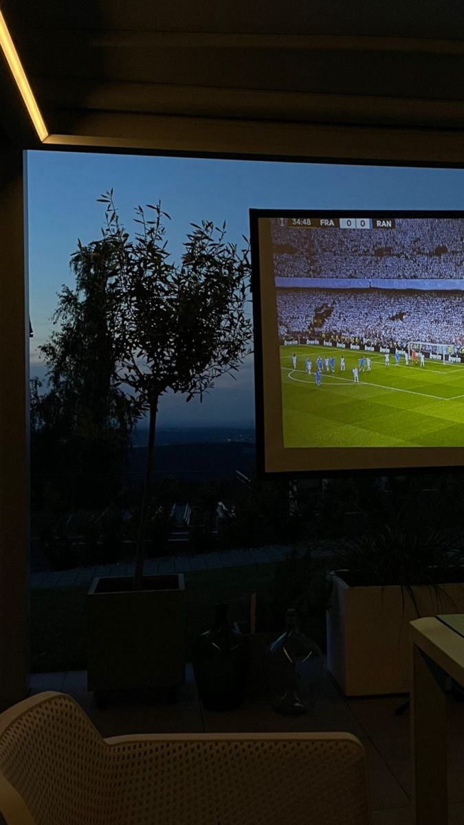 a large screen tv sitting on the side of a wall next to a table and chairs