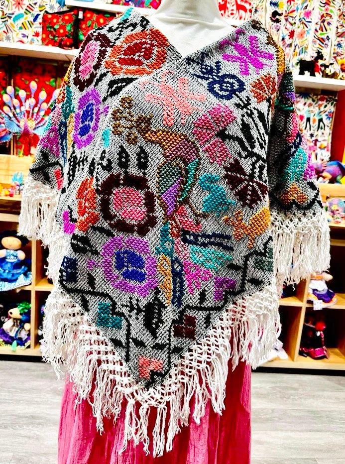 These beautiful Mexican ponchos (aka mañanitas) are handmade in Hueyapan Puebla. Every poncho bears unique hand-embroidery according to the traditions of the community. Measuring approximately 34" wide by 26'' long, one size should fit all adults. All ponchos can be worn 2 ways: Flat across the front or point down, for a longer, more flowing look. (Each piece may slightly vary from the model in the photo) Black Peacock, Mexican Gifts, Mexican Outfit, Kids Menu, Mexican Jewelry, Tropical Decor, Scarf Jewelry, The Community, Ponchos