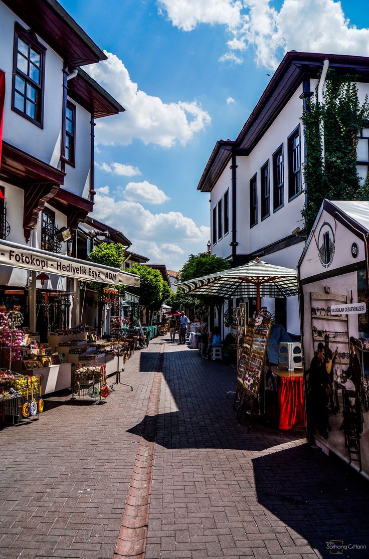 an open air market on the side of a road in front of some white buildings