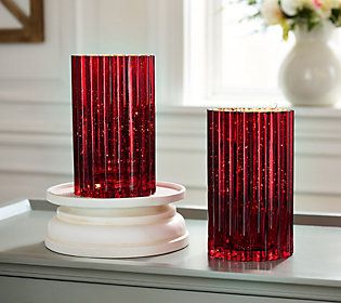 two red glass vases sitting on top of a white table next to each other