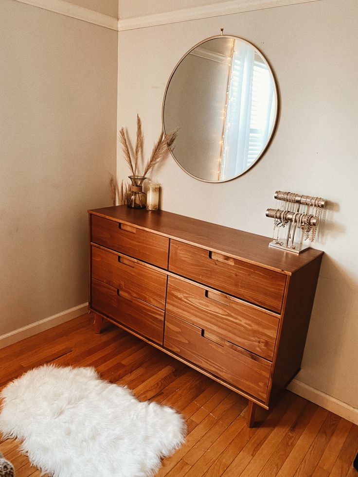 a wooden dresser sitting on top of a hard wood floor next to a white rug