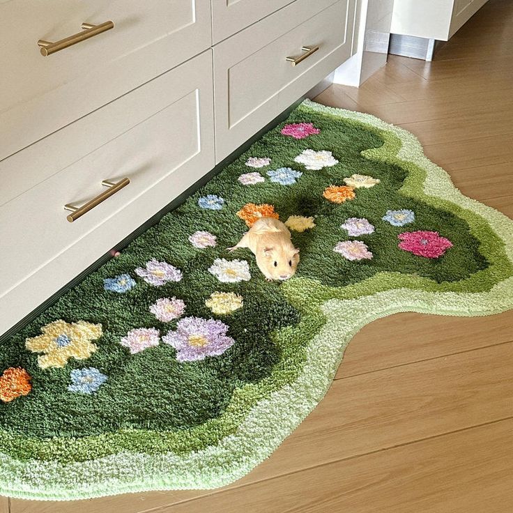 a hamster is laying on a rug in the middle of a kitchen floor with flowers all over it