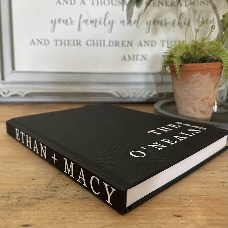 a book sitting on top of a wooden table next to a potted plant