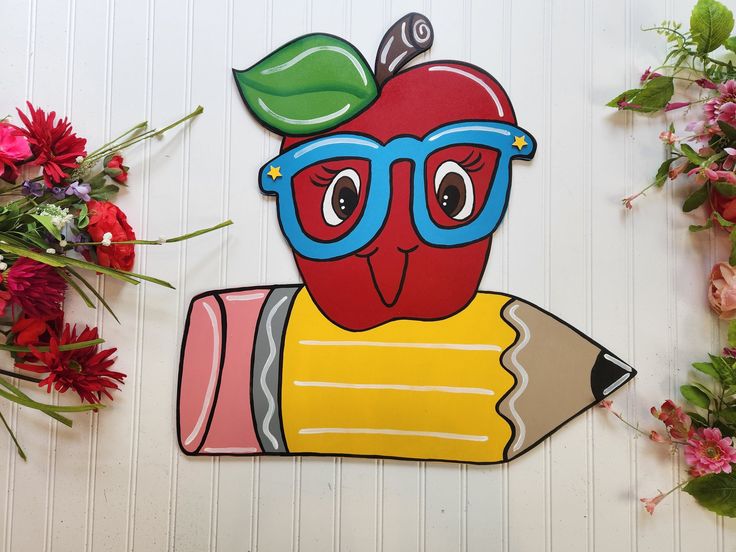 an apple wearing glasses and holding a pencil in front of some flowers on the wall