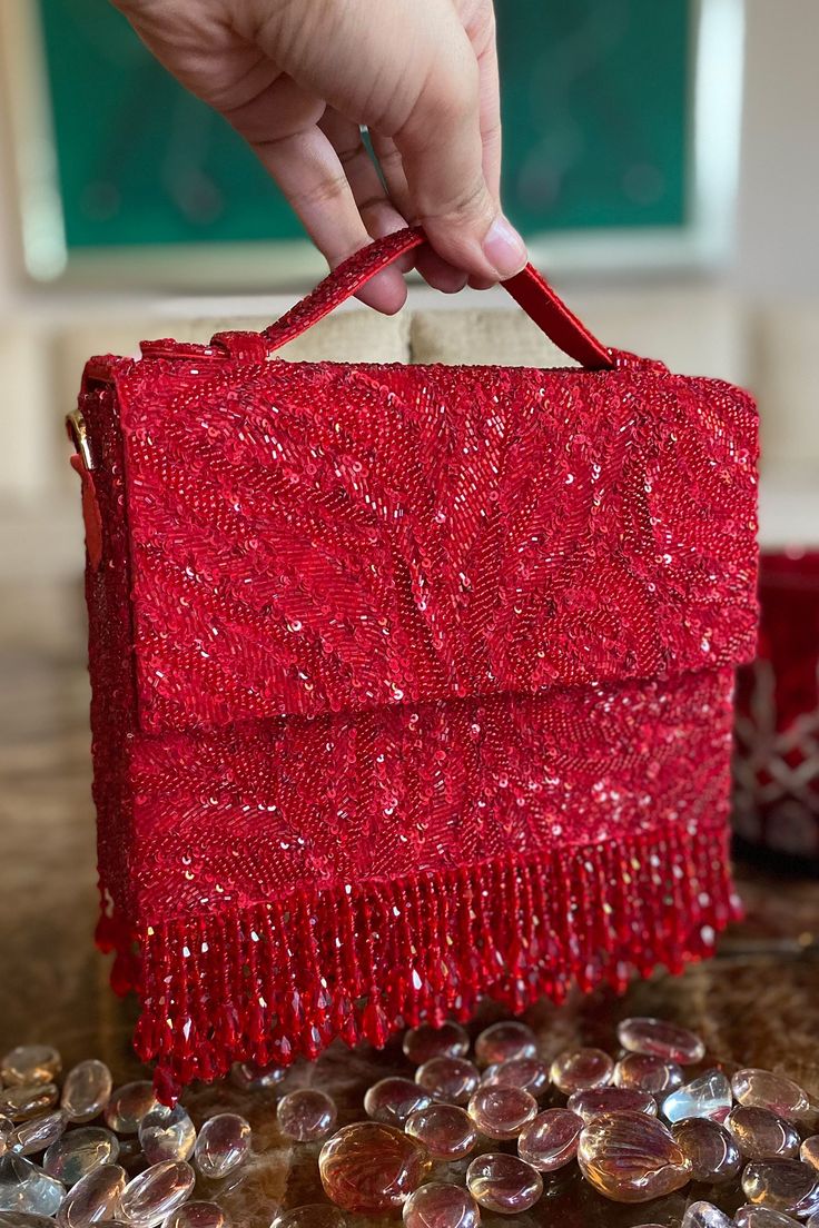 Red box shaped clutch with all-over sequin and bead embellishment and has a handle on top. Comes with a chain sling.
Type:Beads and Sequin
Compositon:Poly Silk
Color:Red
Other Details:
Bead drops at the bottom
Dimensions L x W (inch): 5.5 x 7.5
Closure: Snap magnetic button - Aza Fashions Luxury Red Box Bag For Evening, Hand Embellished Rectangular Evening Bag For Party, Red Top Handle Clutch For Formal Occasions, Formal Red Clutch With Top Handle, Formal Red Top Handle Clutch, Red Embellished Evening Bag, Rectangular Sequined Party Clutch, Rectangular Sequin Party Clutch, Red Handcrafted Evening Bag For Party