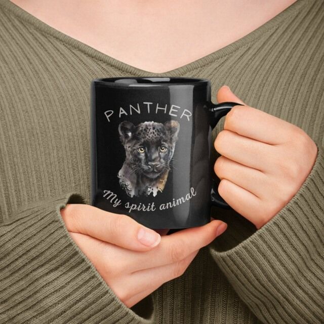 a woman holding a coffee mug with a black panther on it