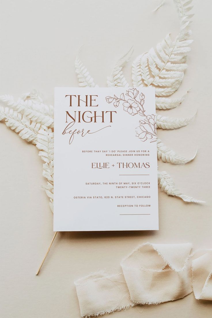 the wedding suite is laid out on top of some white cloths and feathers, with an envelope that says the night