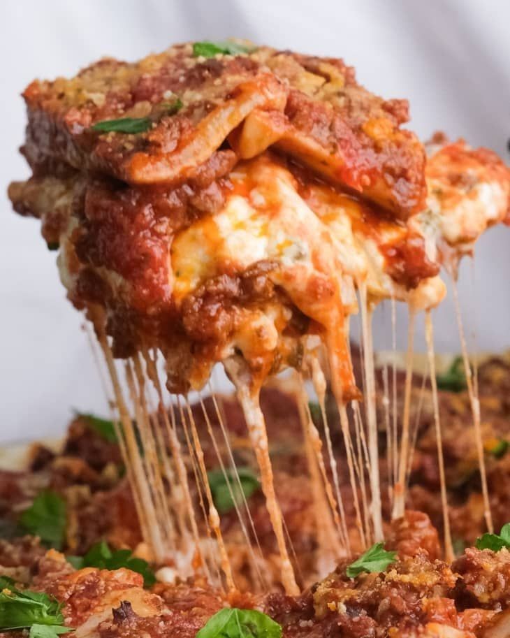 a close up of a pizza with cheese and sauce being lifted from the pan by a spatula