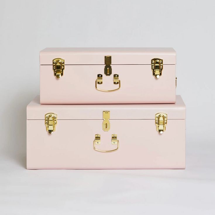 two pink suitcases sitting side by side on top of each other with gold handles