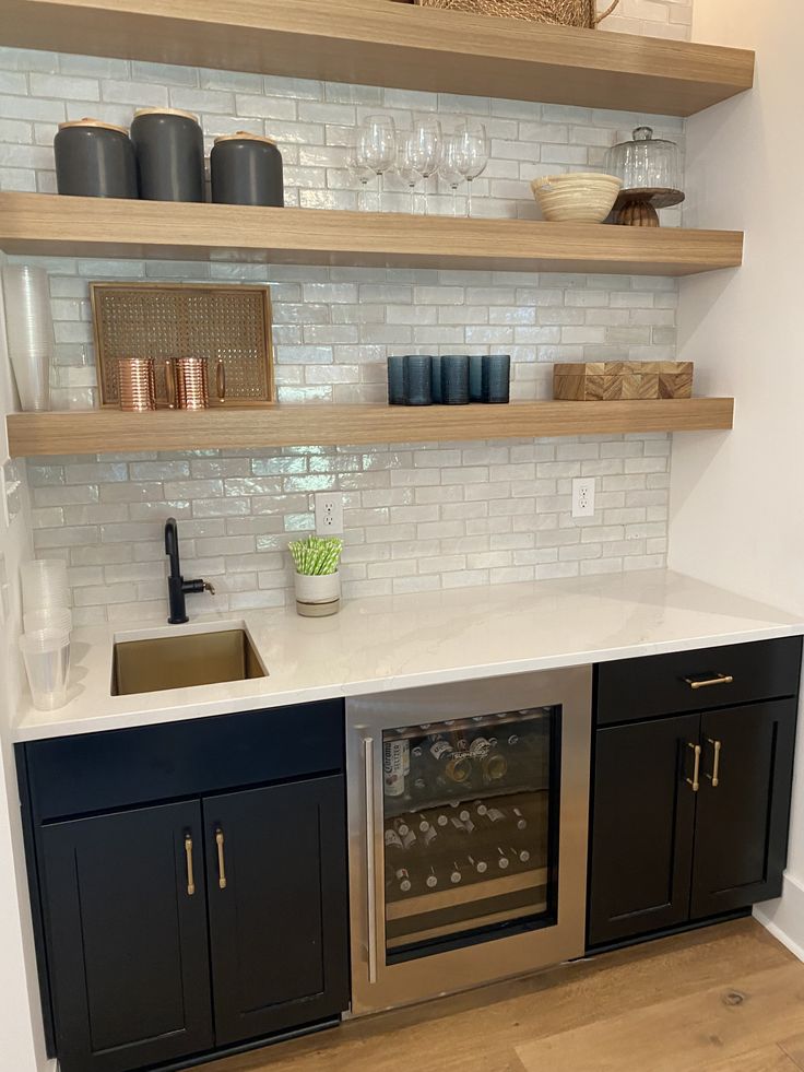 a kitchen with open shelving above the sink and wine glasses on the counter top