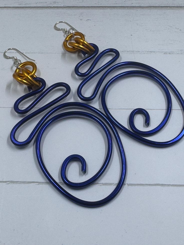 These Blue and Gold colored Abstract Aluminum Wire earrings will be a hit all summer long!  Handmade each pair is a little different so you will have a unique pair of earrings made just for you!  Turn heads at all of the brunch spots with these light weight, hypo allergenic non tarnishing earrings.  Made with sterling silver ear wire. How often you you see Blue jewelry?  Pair earrings with a Ring or Cuff Bracelet custom made to fit! Wire Earrings Handmade, Wire Wrapped Jewelry Diy, Flat Wire, Wire Jewelry Designs, Brunch Spots, Colorful Jewelry, Wrapped Jewelry, Blue Jewelry, New Crafts