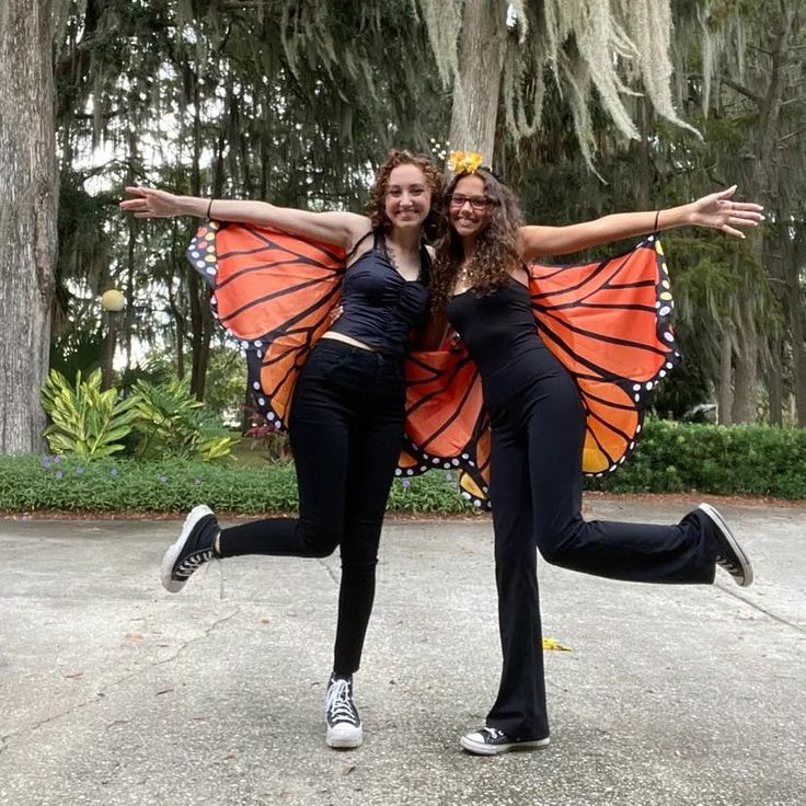 two women dressed in butterfly wings pose for the camera