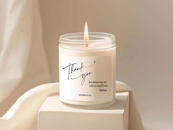 a white candle sitting on top of a box with the words thank you written on it