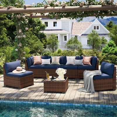 an outdoor living area with blue couches and pillows on the floor next to a swimming pool