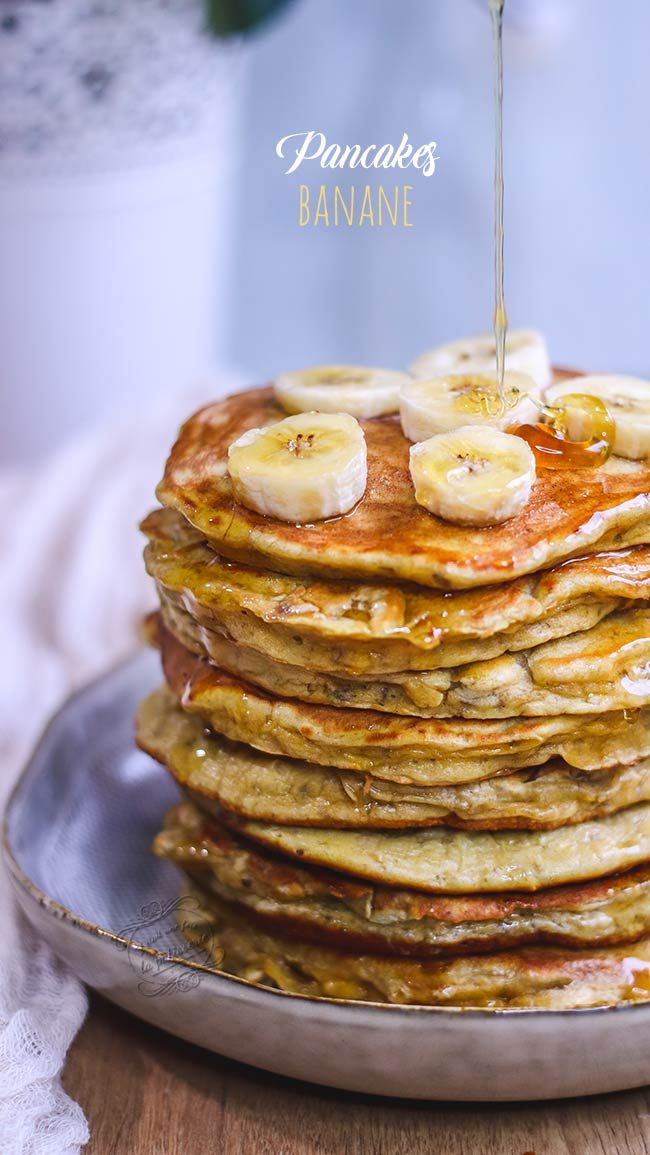 a stack of pancakes with bananas and syrup being drizzled on top